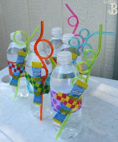 three plastic water bottles are lined up on a table with toothbrushes and streamers