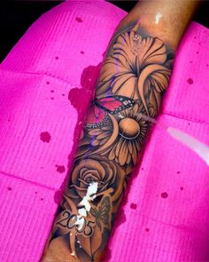 a woman's arm with flowers and butterflies on it, while she is wearing a pink shirt