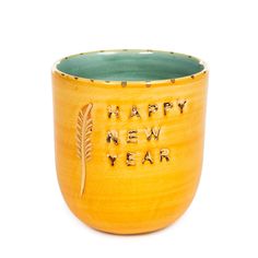 a yellow ceramic cup with the words happy new year written on it and an arrow