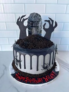 a cake decorated with black and white frosting, spooky hands and tombstones