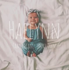 a baby laying on top of a bed wearing a headband and smiling at the camera