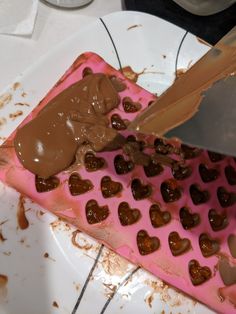 someone cutting into a heart shaped cake with chocolate icing and hearts on the top