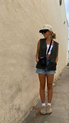 a woman standing in front of a wall with her back to the camera and wearing a hat