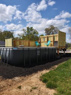 an above ground swimming pool in the middle of a yard with chairs and storage boxes