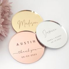 three personalized wedding coasters with the names and date on them next to pink flowers