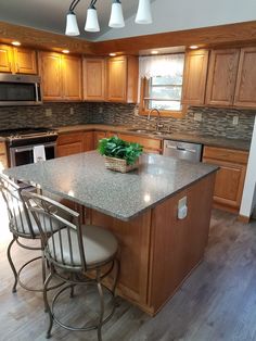 a kitchen with an island and three stools next to the counter top in front of it