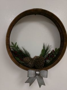 a wreath with pine cones and evergreens is hanging on the wall