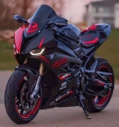 a black and red motorcycle parked on top of a brick road in front of a house