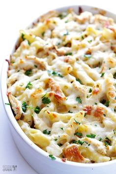 a casserole dish with chicken, cheese and parsley in it on a white surface