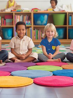 four children sitting on the floor in front of colorful rugs