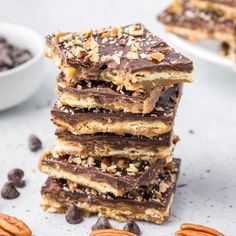 a stack of chocolate pecan bars on top of each other with nuts around them