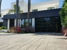 a house with palm trees in front of it and two garages on the other side