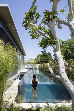 a woman in a bathing suit is standing by the pool and looking at the water