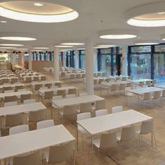 an empty classroom with white tables and chairs