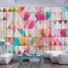 a living room filled with white furniture and colorful wall art on the side of it