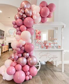 the balloon column is decorated with pink, white and silver balloons for an elegant birthday party