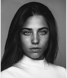 a black and white photo of a woman with freckles on her face looking at the camera