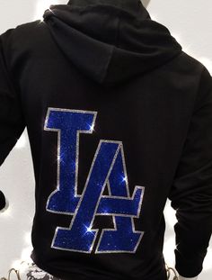 Super sparkle LA rhinestone hoodie. This stunning hoodie has a large sapphire rhinestone LA logo on the back. Front has smaller silver LA logo on the left side, and a bling string!! We use high quality, multi-cut rhinestones for all our designs. This makes them super sparkly and really cool. Perfect to wear to a Dodger game, to the beach or anytime! Great gift for any fan of the Dodgers or LA! Nice weight black fleece hoodie is a unisex fit. Please check the measurements below, you maybe able to Cheer Moves, Diamond Hoodie, Rhinestone Hoodie, Dodger Game, Causual Outfits, Black Fleece, Black Rhinestone, Small Chest, Fan Gear