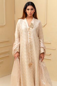 Expertly crafted from luxurious khaadi silk, this beige shalwar kameez boasts a stunning jamawar mesore dupatta and silk trousers. The hand sewn pearl details on the sleeves and neckline add a touch of elegance to this traditional ensemble. Elevate your style with this timeless piece. 3-Piece Suit Long Sleeve Raw Silk Anarkali Set For Eid, Silk Anarkali Set For Eid With Long Sleeves, Tussar Silk Sherwani For Eid, Elegant Cream Cotton Silk Traditional Wear, Cream Salwar Kameez With Zari Work In Cotton Silk, Cream Cotton Silk Salwar Kameez For Diwali, Diwali Cotton Silk Cream Salwar Kameez, Diwali Cream Cotton Silk Salwar Kameez, Raw Silk Long Sleeve Kurta With Dupatta