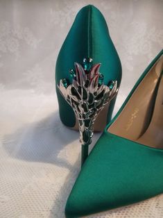 a pair of green high heeled shoes sitting on top of a white table cloth