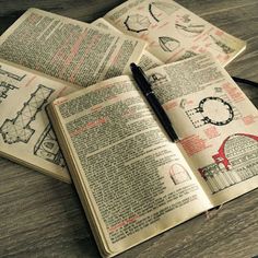 an open book sitting on top of a wooden table next to a pen and glasses