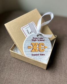 an ornament in a gift box with a name tag on it that says xc