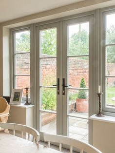 a dining room table and chairs with large windows in the back ground area, looking out onto an outdoor courtyard