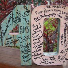 a wooden sign with writing on it sitting in front of a tree and some bushes