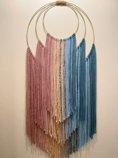 a multicolored wall hanging on a white wall with metal hoop and circular rings