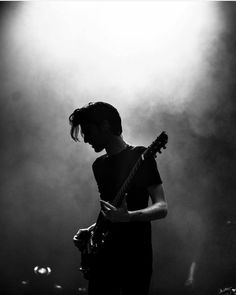 a man standing in front of a microphone while holding a guitar