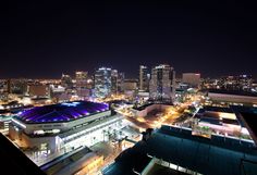 an aerial view of a city at night with lights on and buildings lit up in the background