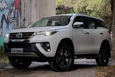 a white suv parked in front of a graffiti covered wall