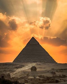 the sun shines through clouds over an ancient pyramid in egypt, with rays coming from behind it