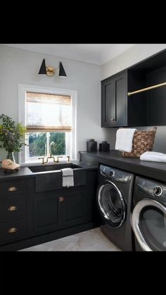 a washer and dryer in a small room with dark wood cabinets, black counter tops, and white walls