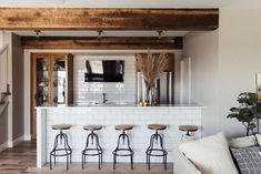 a living room filled with furniture and a flat screen tv mounted to the wall above a bar