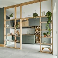 a living room filled with lots of furniture and plants on top of wooden bookshelves