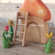 a wooden toy house with flowers and a ladder