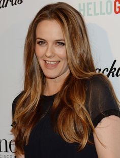 a woman with long brown hair smiling at the camera