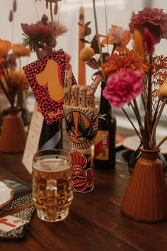 a table topped with bottles and vases filled with flowers next to each other on top of a wooden table