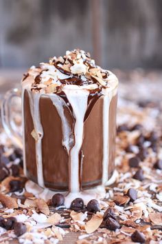 a glass mug filled with hot chocolate and marshmallows on top of coffee beans