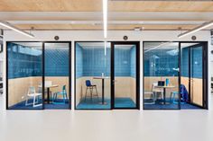 an empty room with glass walls and blue tile on the wall, as well as tables and chairs