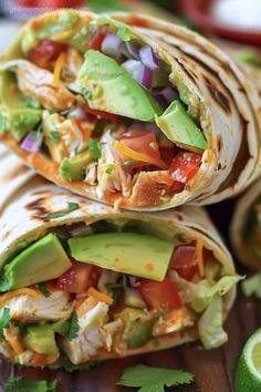 two burritos filled with chicken, avocado and tomatoes