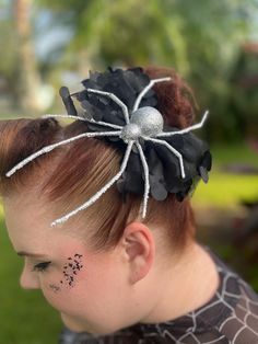 a woman with red hair wearing a black spider costume and silver glitters on her face