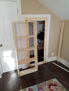 an unfinished bookcase in the corner of a room next to a door and rug