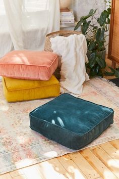 three different colored cushions on the floor