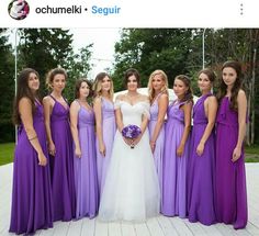 a group of women standing next to each other wearing purple dresses and holding bouquets