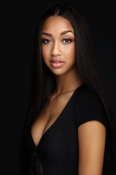 a beautiful young woman with long hair posing for a photo in front of a black background