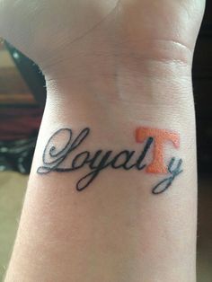 a wrist tattoo with the letter t on it