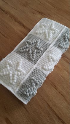 a crocheted white and gray tie on a wooden table