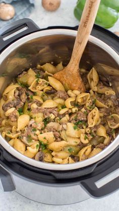 a pot filled with pasta and meat on top of a table next to garlic, mushrooms and parsley